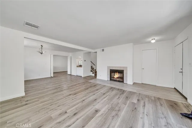 a view of an empty room with wooden floor fireplace and a window