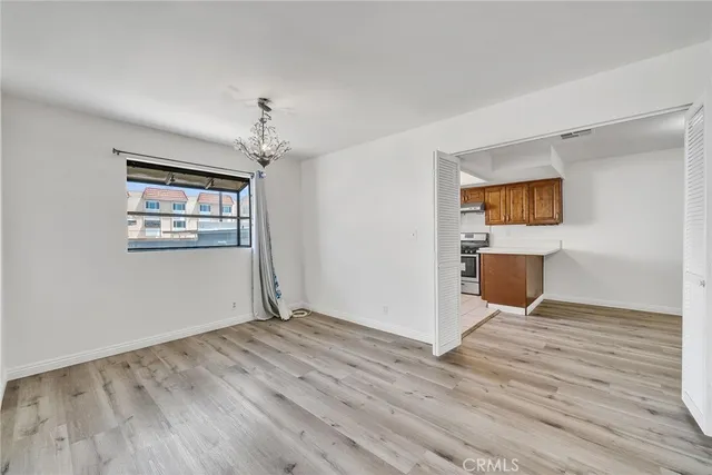 an empty room with wooden floor chandelier and windows