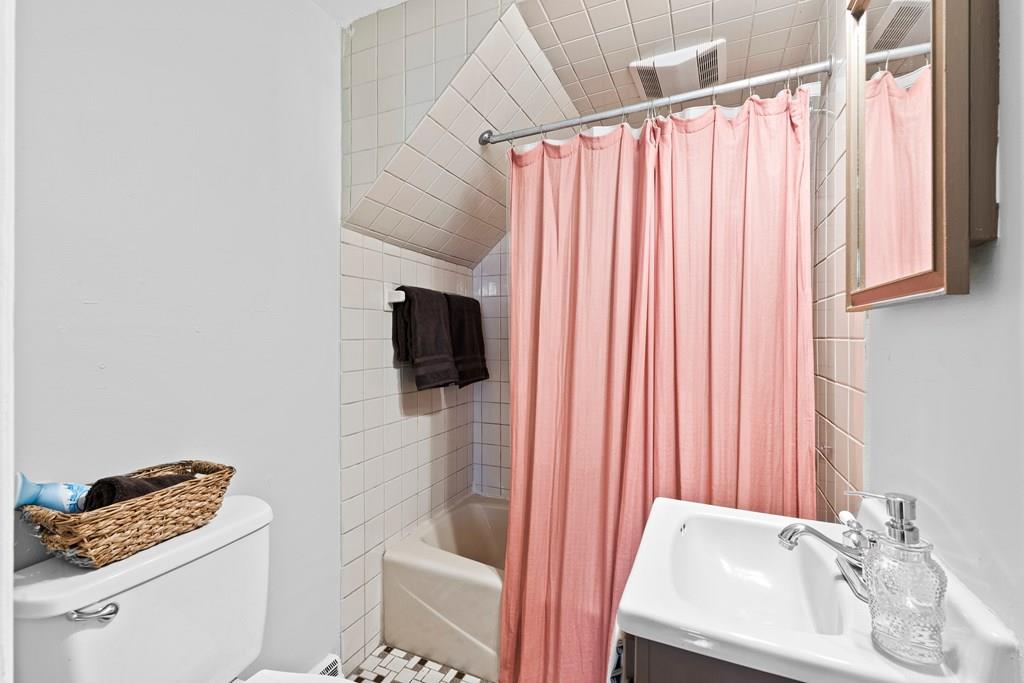 143 18th Street Lowell, MA 01850 - Photo 16 of 35 a bathroom with a sink a toilet and a shower curtain