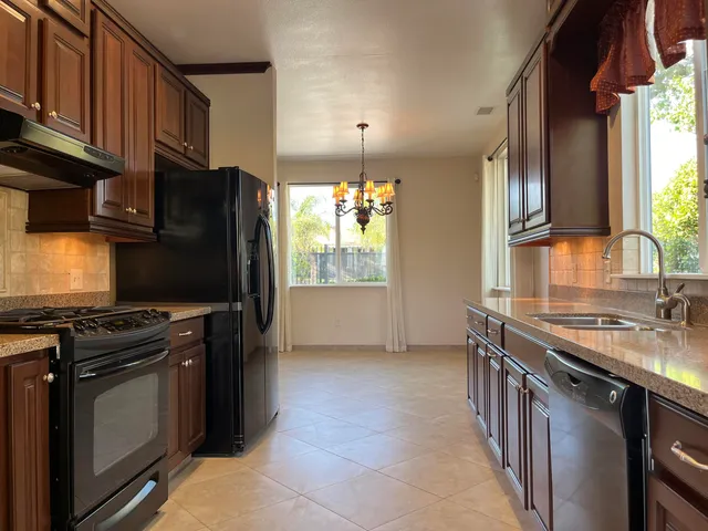 a kitchen with granite countertop stainless steel appliances a refrigerator and a sink
