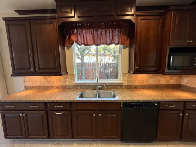 a kitchen with granite countertop wooden cabinets and stainless steel appliances