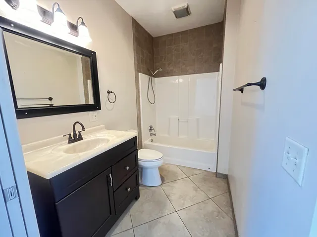 a bathroom with a granite countertop sink a toilet and a window