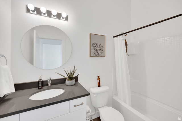 7713 Navarro View Court Midvale, UT 84047 - Photo 22 of 41 Bathroom featuring a white vanity with brushed nickel hardware, a dark countertop, an undermount sink, and a circular mirror
