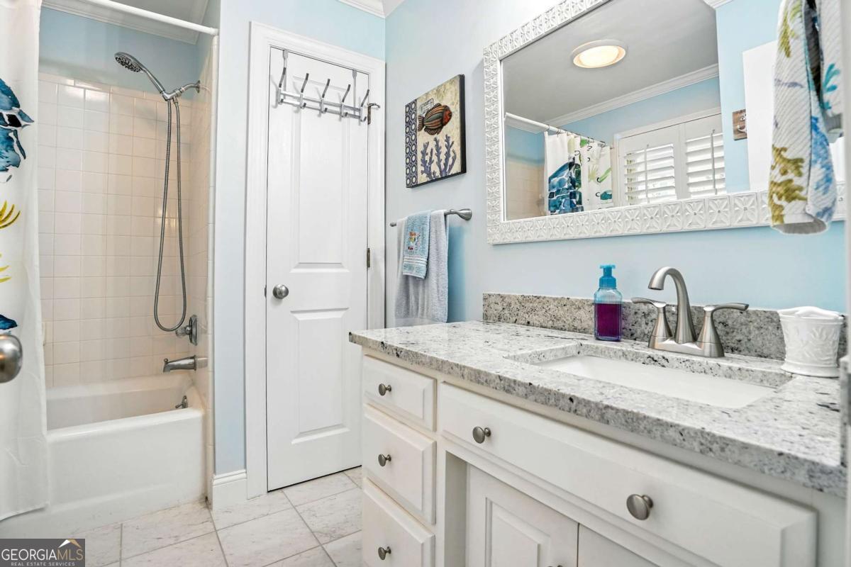 202 Vassar Point Drive St. Simons, GA 31522 - Photo 29 of 62 a bathroom with a granite countertop sink a mirror a bathtub and shower