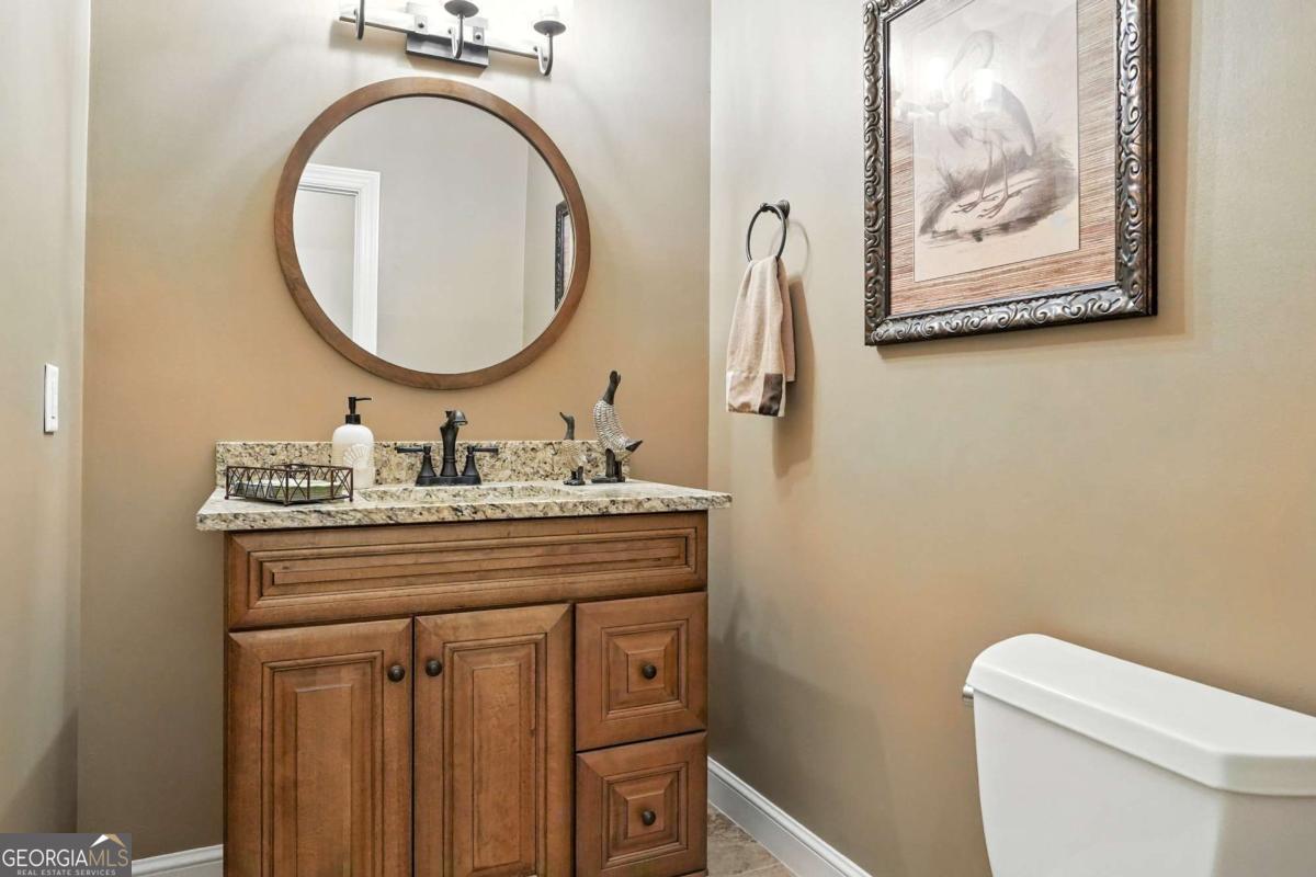 202 Vassar Point Drive St. Simons, GA 31522 - Photo 39 of 62 a bathroom with a granite countertop toilet a sink and a mirror