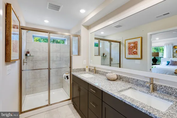 a bathroom with a granite countertop sink a mirror and shower