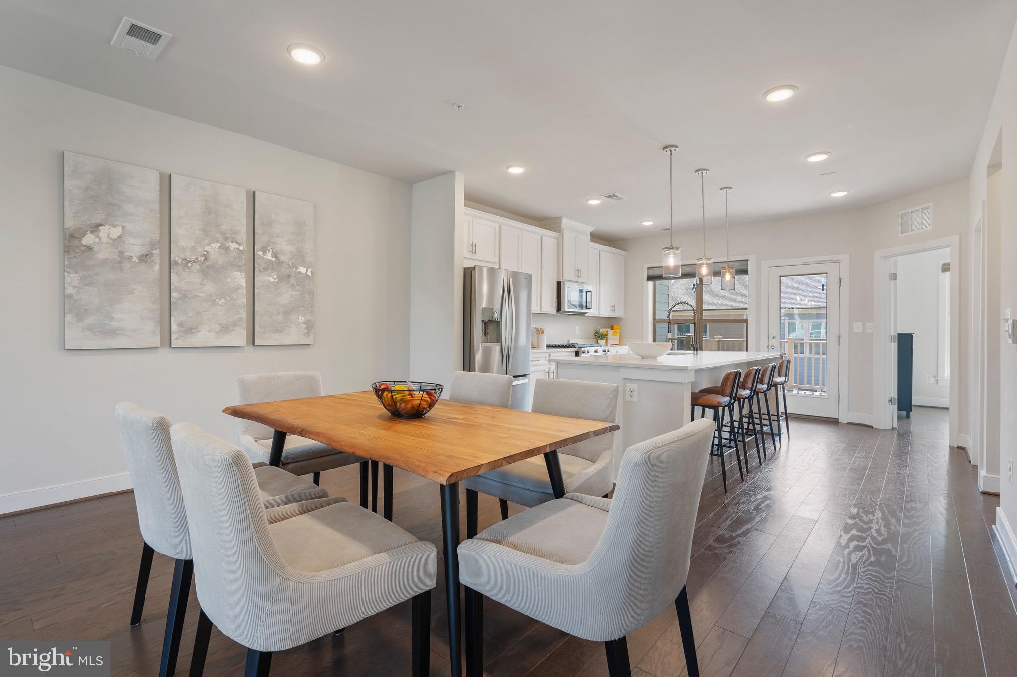 9580 Fields Road Gaithersburg, MD 20878 - Photo 5 of 58 a dining room with stainless steel appliances kitchen island granite countertop a dining table chairs and wooden floor