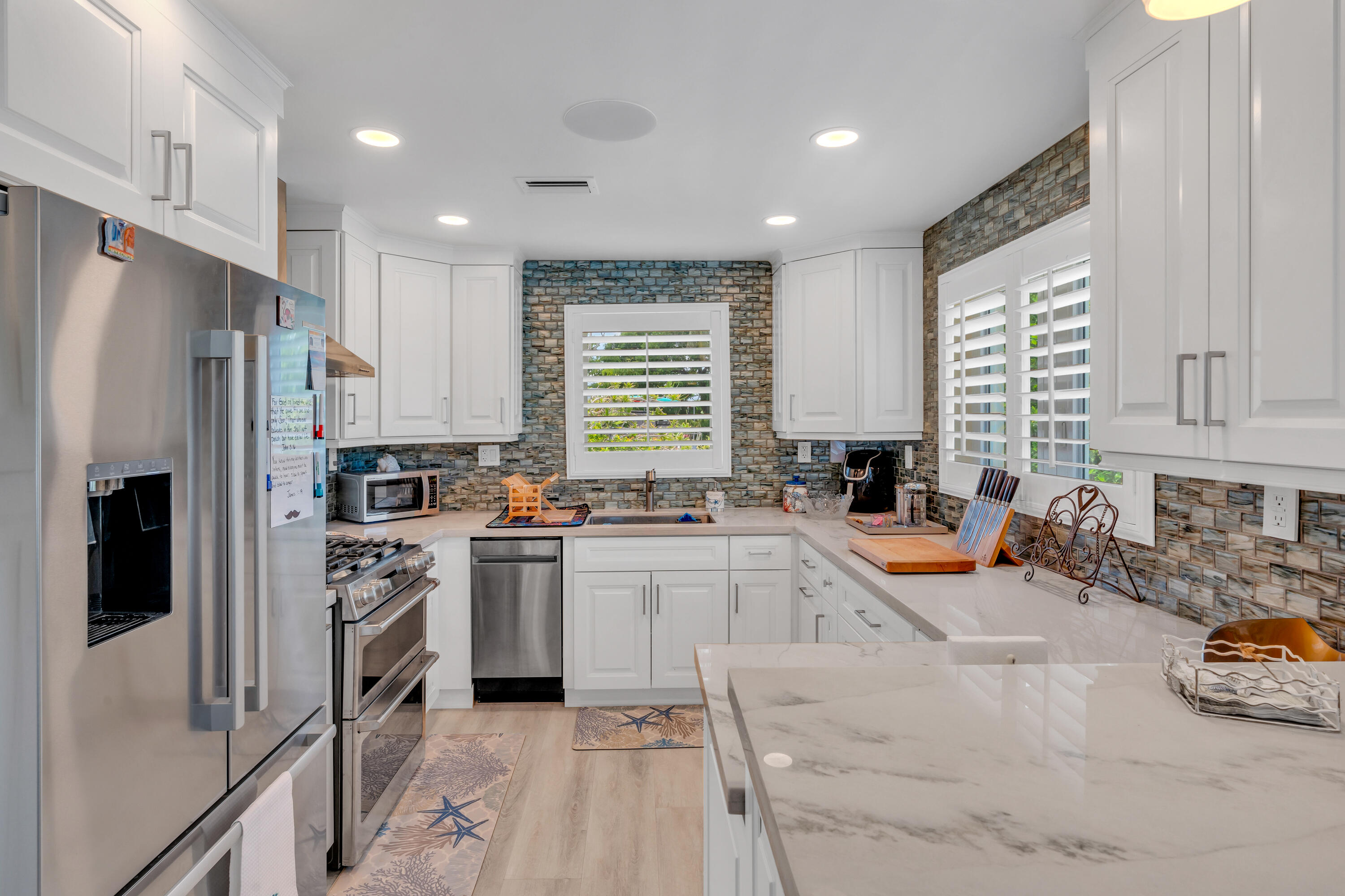 129 Pirates Drive Key Largo, FL 33037 - Photo 6 of 42 a kitchen with stainless steel appliances granite countertop a refrigerator a sink dishwasher a stove and white cabinets with wooden floor