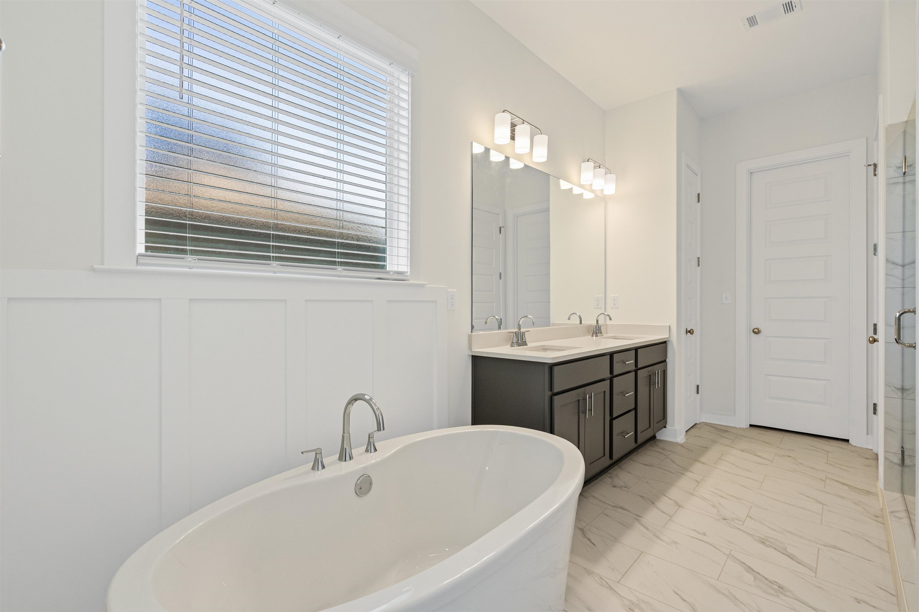 5666 Pleasant Pk Place Arlington, TN 38002 - Photo 20 of 27 Freestanding soaking tub with polished chrome fixtures, dual vanity with undermount sinks and quartz-style countertop, full-height mirror, and tile flooring