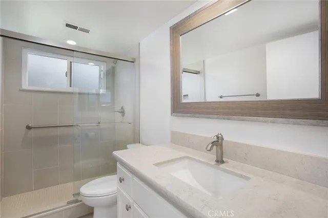 a bathroom with a granite countertop sink a toilet and shower