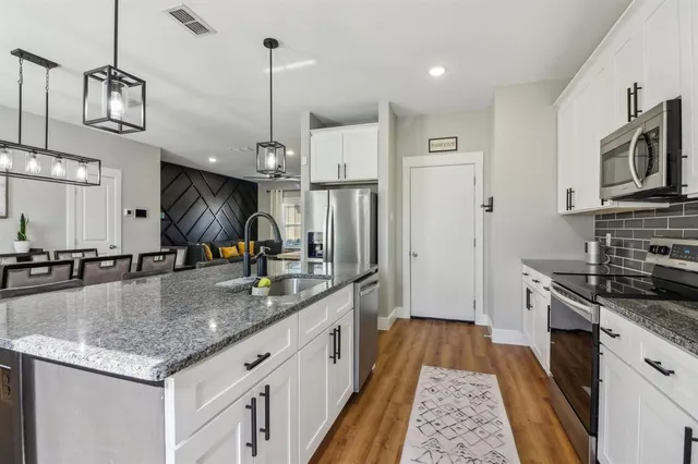a kitchen with stainless steel appliances granite countertop a sink a stove and a refrigerator