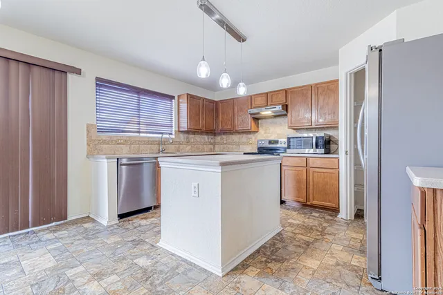 a kitchen with stainless steel appliances granite countertop a refrigerator a sink dishwasher a stove with wooden cabinets