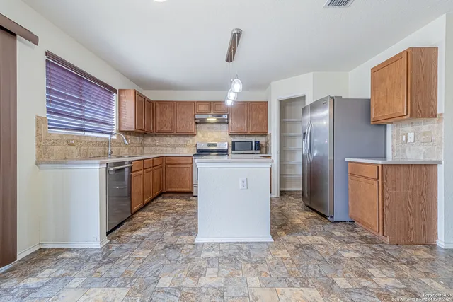 a kitchen with a sink a stove a refrigerator and cabinets