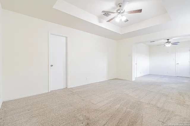 an empty room with a chandelier fan and windows