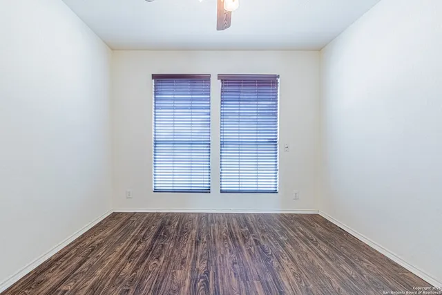 an empty room with wooden floor and fan