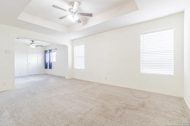 an empty room with a chandelier fan and wooden floor