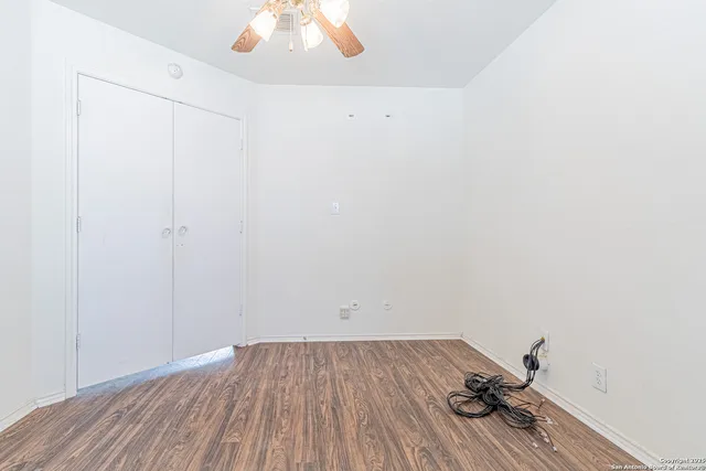 a view of a room with wooden floor and ceiling fan