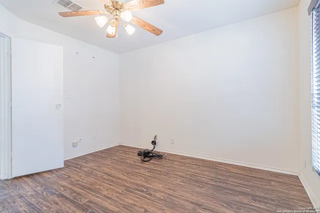 a view of a room with wooden floor and ceiling fan