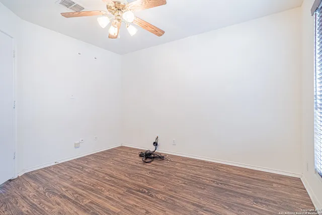 a view of empty room with wooden floor and fan
