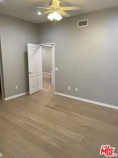 a view of a room with a ceiling fan and wooden floor