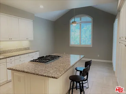 a kitchen with granite countertop a stove a sink dishwasher and cabinets with wooden floor