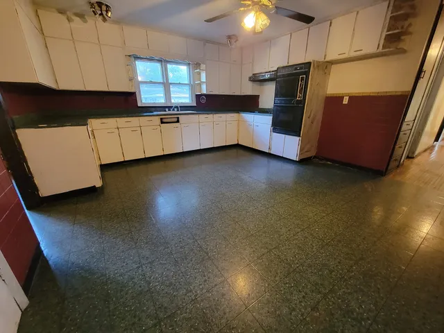 a kitchen with stainless steel appliances a refrigerator a sink a stove white cabinets and wooden floor