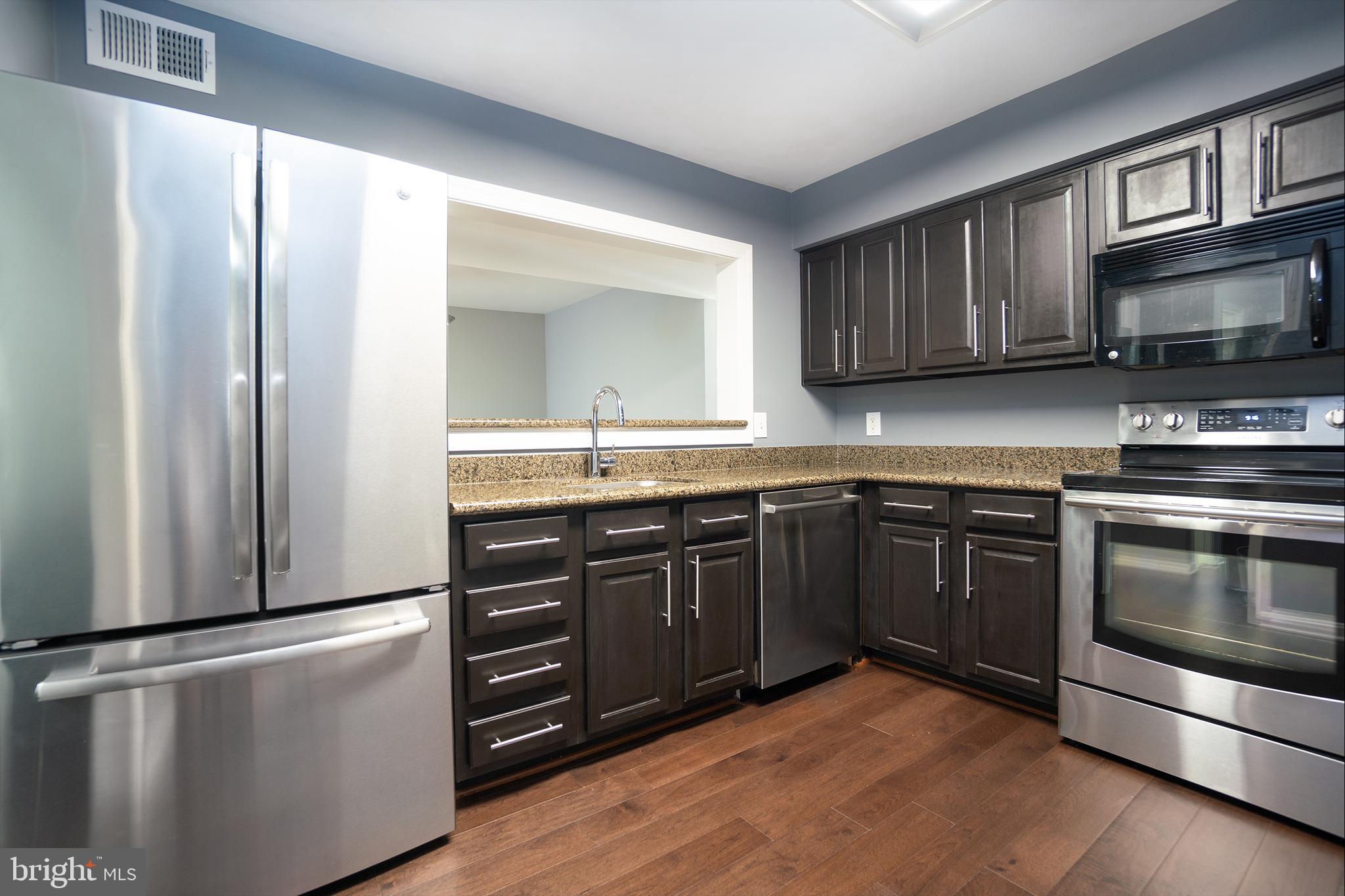10248 Appalachian Circle, Unit 1D7 Oakton, VA 22124 - Photo 7 of 32 a kitchen with stainless steel appliances granite countertop a refrigerator stove a sink and a microwave