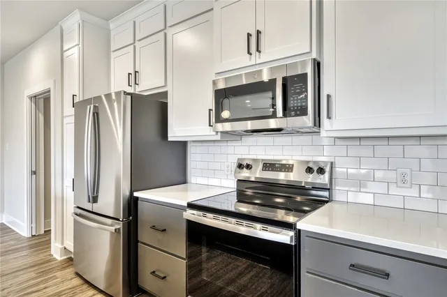 a large kitchen with kitchen island a large window and stainless steel appliances