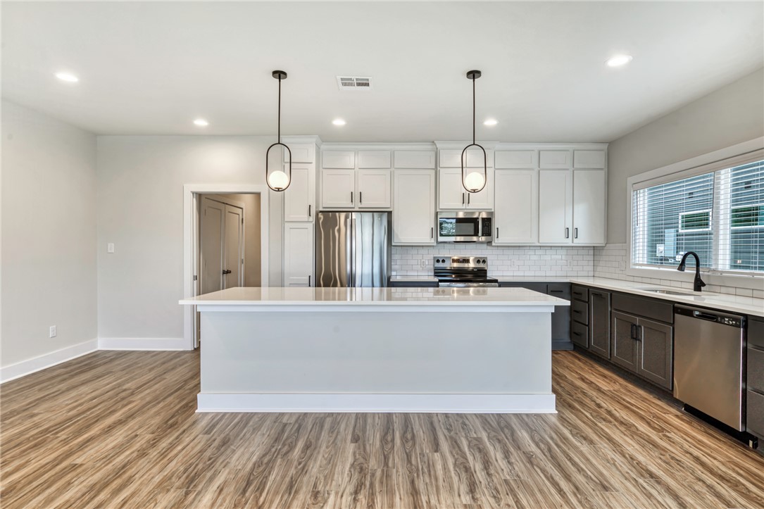 301 Cooner Street, Unit A College Station, TX 77840 - Photo 7 of 36 a kitchen with stainless steel appliances granite countertop a sink a refrigerator a center island a stove and a wooden floors