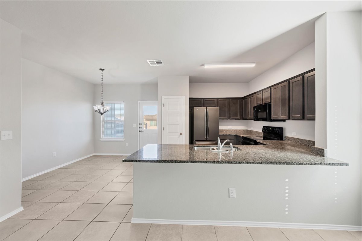 1202 Garland Road Georgetown, TX 78626 - Photo 11 of 28 Open-concept kitchen featuring dark wood cabinetry, granite countertops, stainless steel appliances, and a breakfast bar