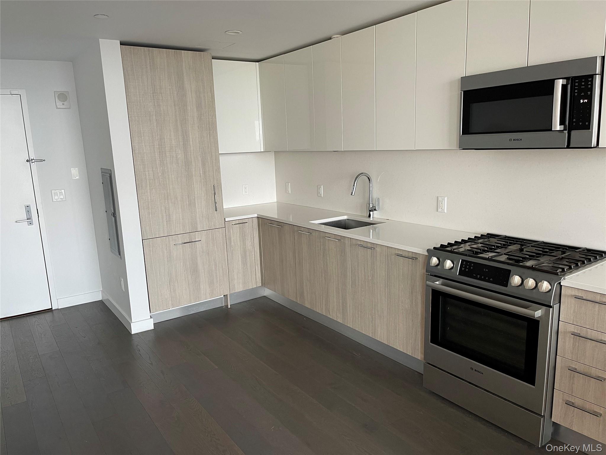 131-05 40 Road, Unit PH1D Queens, NY 11354 - Photo 3 of 23 Kitchen featuring modern cabinets, stainless steel appliances, dark wood finished floors, and light stone countertops