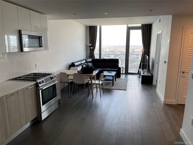 a kitchen with stainless steel appliances a stove a sink a microwave a dining table and chairs with wooden floor