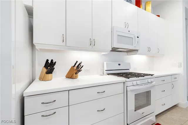 a kitchen with white cabinets and appliances