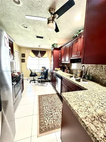 a kitchen with stainless steel appliances kitchen island granite countertop a stove refrigerator and cabinets