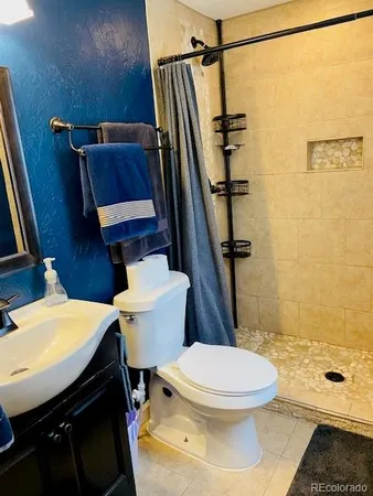 a bathroom with a sink a toilet a mirror and shower