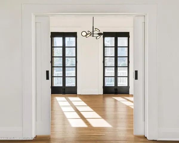 a view of an empty room with window and wooden floor