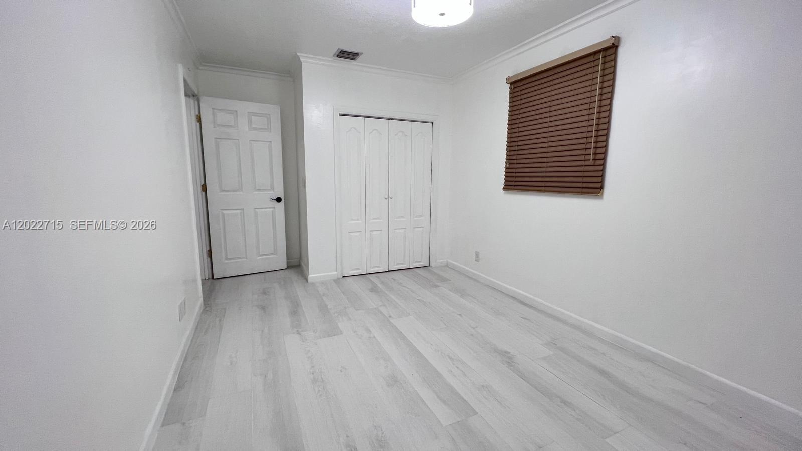 10669 Boca Entrada Boulevard Boca Raton, FL 33428 - Photo 14 of 19 a view of an empty room with wooden floor and a window