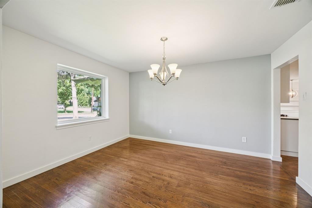 6742 Williamson Road Dallas, TX 75214 - Photo 5 of 11 DINING ROOM Situated at Front of Home and Adjacent to Kitchen, Boasts Wide Doorways, Ovesized Picture Window With Views of Front Yard, Decorative Chandelier, Neutral Colors, and Wood Flooring