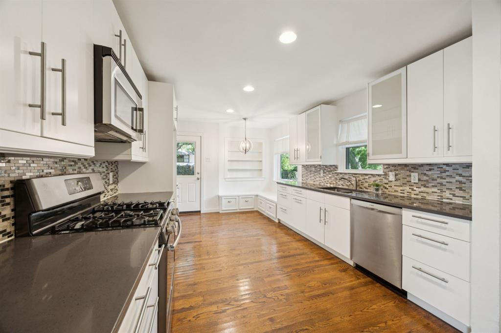 6742 Williamson Road Dallas, TX 75214 - Photo 6 of 11 KITCHEN Boasts Stainless Steel Appliances, 4-Burner Gas Cooktop, Granite Counters, Horizontal Staggered Tile Backsplash, Stainless Steel Double Sink, Display Cabinets, Built-In Shelving, Recessed Lighting and Wood Floors