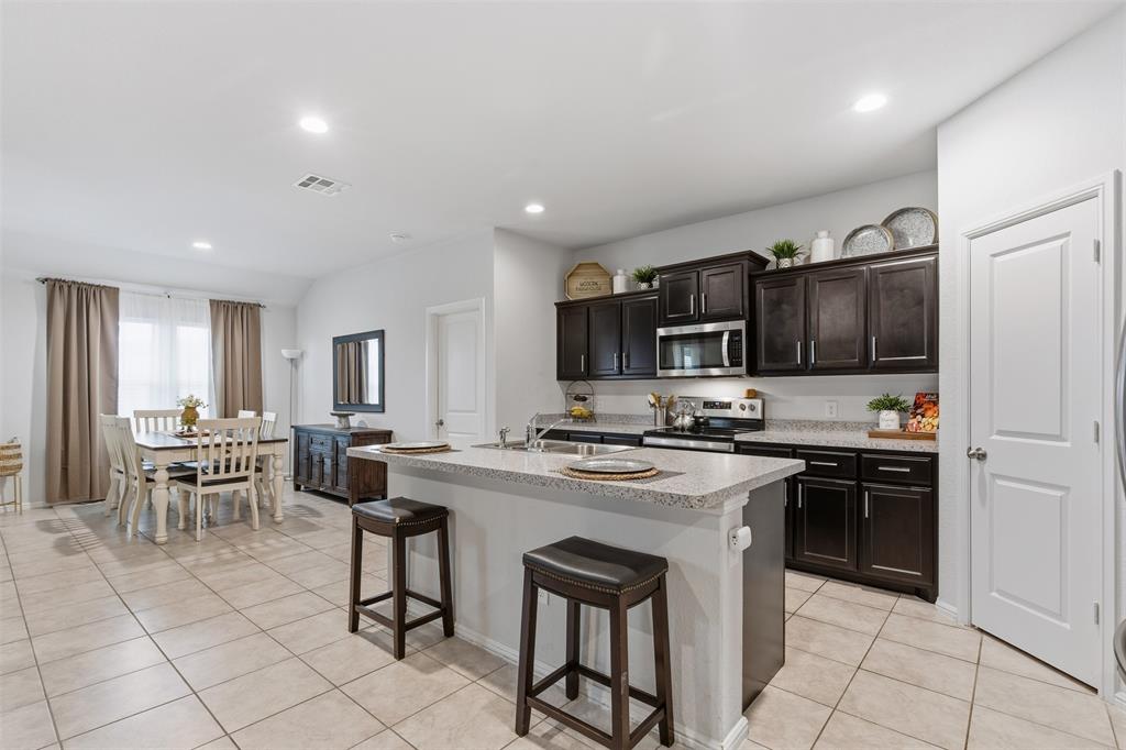 3400 Quiet Valley Road Fort Worth, TX 76123 - Photo 2 of 31 a kitchen with stainless steel appliances granite countertop a stove top oven a sink a dining table and chairs