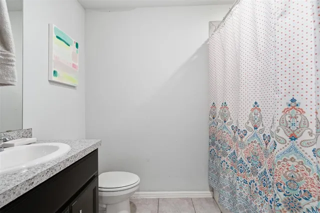a bathroom with a granite countertop sink and a toilet