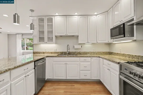 a kitchen with stainless steel appliances granite countertop a stove a sink and a microwave