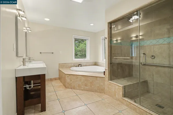 a bathroom with a bathtub shower sink vanity and mirror
