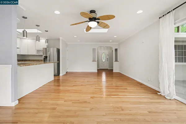 a view of an empty room with kitchen appliances and a ceiling fan