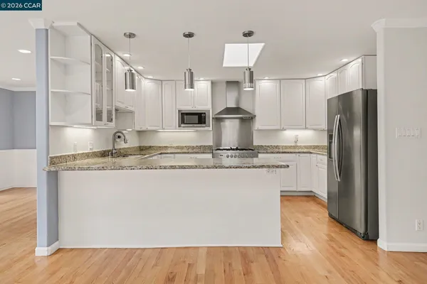 a kitchen with kitchen island granite countertop a refrigerator and a sink