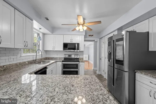 a kitchen with stainless steel appliances granite countertop a refrigerator a stove and a sink with cabinets