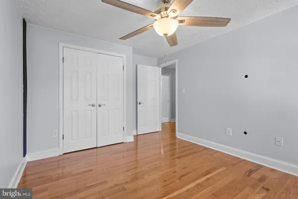 an empty room with wooden floor closet and fan