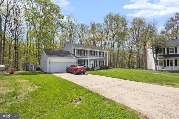 a view of a house with a yard and large trees