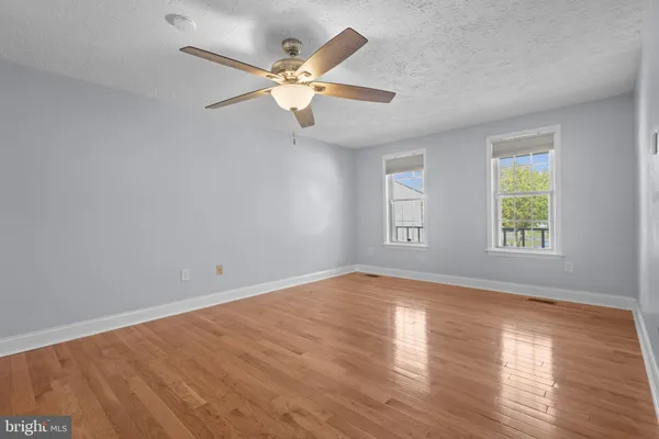 a view of an empty room with window and wooden floor
