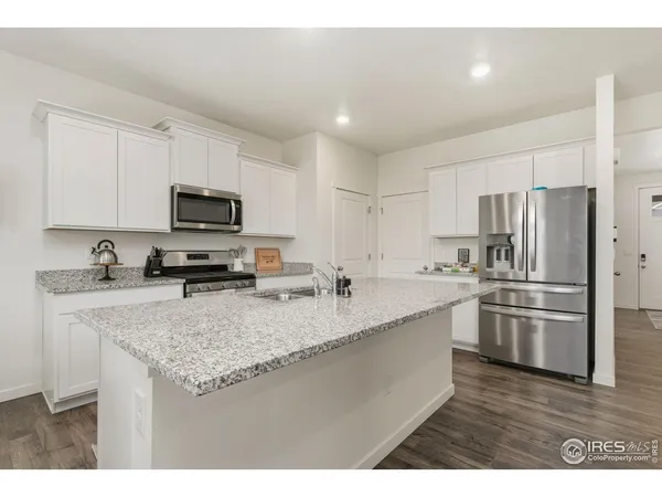 a kitchen with stainless steel appliances granite countertop a sink a stove a refrigerator a center island and cabinets